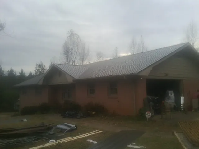 Gray metal roof on a stucco house with an attached garage in Dyer