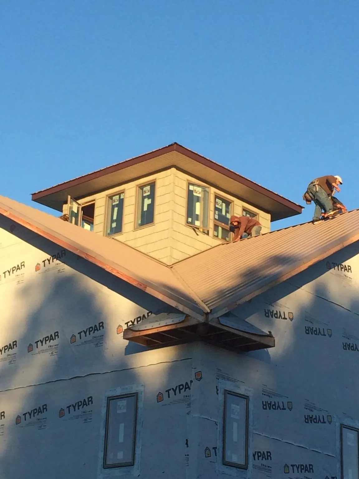 Roofers working around a rooftop cupola on a new metal roof at sunset — Roof Waterproofing in Dyer by Roofing Brothers